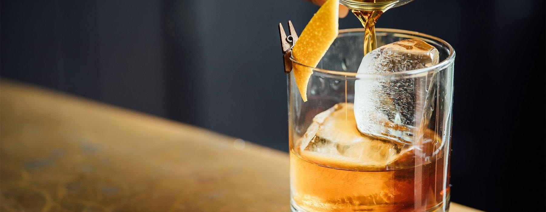 a glass of liquid being poured into a glass with ice